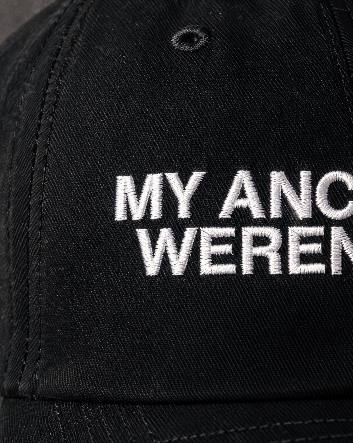 Close-up of the white My Ancestors Weren't Evil embroidery on the black hat